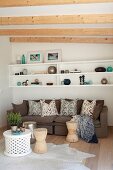 White shelves on wall above sofa with scatter cushions in comfortable lounge area