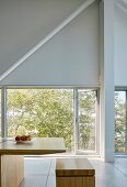Minimalistischer, hoher Essbereich mit Designer-Holzmöbeln vor Terrassentür