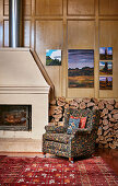 Upholstered armchairs in front of wood storage and fireplace on cassette paneling