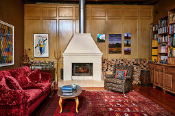 Upholstered armchairs in front of wood storage, fireplace and red sofa with velvet upholstery in the living room