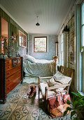 Rustic chair, antique chest of drawers and bed in bedroom in converted stable