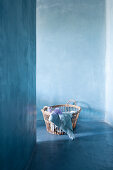 Basket of blue textiles on blue floor against blue wall