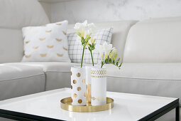Elegant hand-made vases on golden tray on coffee table