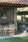 Holztisch auf überdachter Terrasse im mediterranen Garten