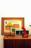 Retro radio, telephone, table lamp and framed picture on sideboard