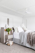 Betthaupt aus Holz mit integriertem Nachtkästchen am Doppelbett in weißem Schlafzimmer