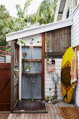 Vintage outdoor shower, surfboard leaning against wall