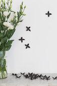 Schwarze Dekoblumen neben einen Blumenstrauß mit weißen Nelken