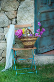Basket of flowers on folding chair against stone wall