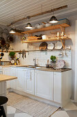Ceiling lamps hung from branch and open shelving in country-house kitchen