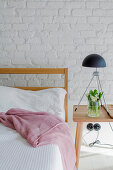 Simple wooden furniture in bedroom with white-painted brick wall