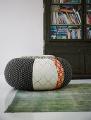 Pouffe with different patterns on green rug in front of cabinet