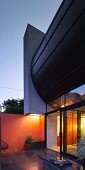 Architect-designed house with glass wall at dusk
