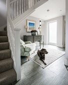 Dog lying on rug in hallway at foot of staircase