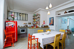 Colourful furniture and dining table in open-plan kitchen of period building