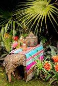 Colourful rug and ornaments on wooden elephant in exotic garden