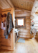 Coat rack on partition wall in rustic bathroom of log cabin