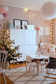 Christmas tree and pompoms in child's bedroom in pastel shades