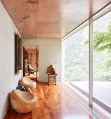 Wooden sculptures in hallway with glass wall, concrete walls and wooden floor