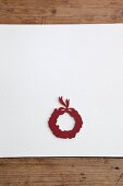 Christmas wreath cut out of red paper on white surface