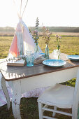 Romantically set table in front of teepee in meadow