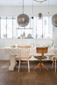 Spherical silver lamps above dining table and various chairs