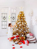 Girl with angel wings in front of golden Christmas tree
