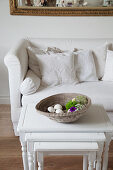 Schale auf einem Set Beistelltische vor dem Sofa mit weißen Kissen