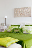 Grüne Bettwäsche und Zierkissen mit Ornamenten auf dem Bett