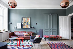 Eclectic furnishings and petrol-blue walls in living room with panelled doors