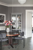 Grey upholstered chairs at round table in room with grey walls