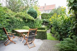 Garden furniture on terrace in lush green garden