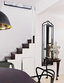 View across dining table to console table against tall wall-mounted mirror and staircase