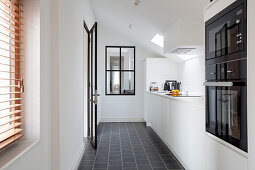 weiße Einbauküche mit schwarzen Bodenfliesen und Dachschräge