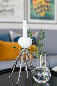 Oktopus-förmiger Kerzenhalter und Glasvase mit Blätterzweig auf Couchtisch