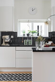 Blick in weiße Küche mit schwarzem Fliesenspiegel
