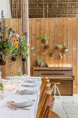 Flower arrangements suspended over set dining table in converted barn