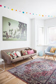 Scatter cushions on retro sofa below large photo on living room wall