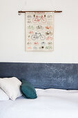 Stripe of chalkboard paint below poster of bicycles on white wall next to bed in child's bedroom