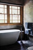 Freestanding bathtub in front of lattice windows in the gray bathroom