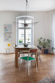 Wooden table and various chairs in front of window in period apartment