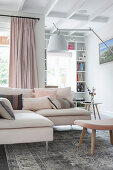 Scatter cushions on pale corner sofa in open-plan interior