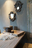 Two mirrors in ornate frames on grey wall above wooden table
