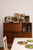 Photos on high sideboard with dining table in foreground