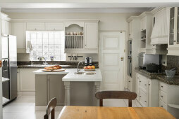 L-shaped counter in renovated country-house-style kitchen with dining area in foreground