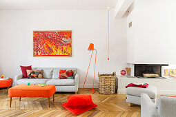 Lounge mit grauen und orangefarbenen Polstermöbeln vor Kamin