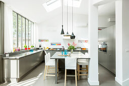 Elegante Küche in Grau und Weiß mit Fensterfront und Esstisch