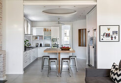 Wooden counter and barstools in white fitted kitchen