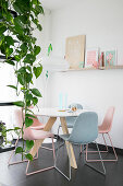 Trailing devil's ivy in front of round dining table with pastel chairs