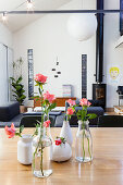 Vases of roses on dining table in front of log burner in lounge area